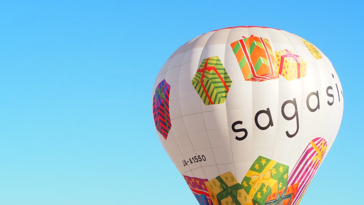 Vibrant hot air balloon with gift designs sailing under a clear blue sky.